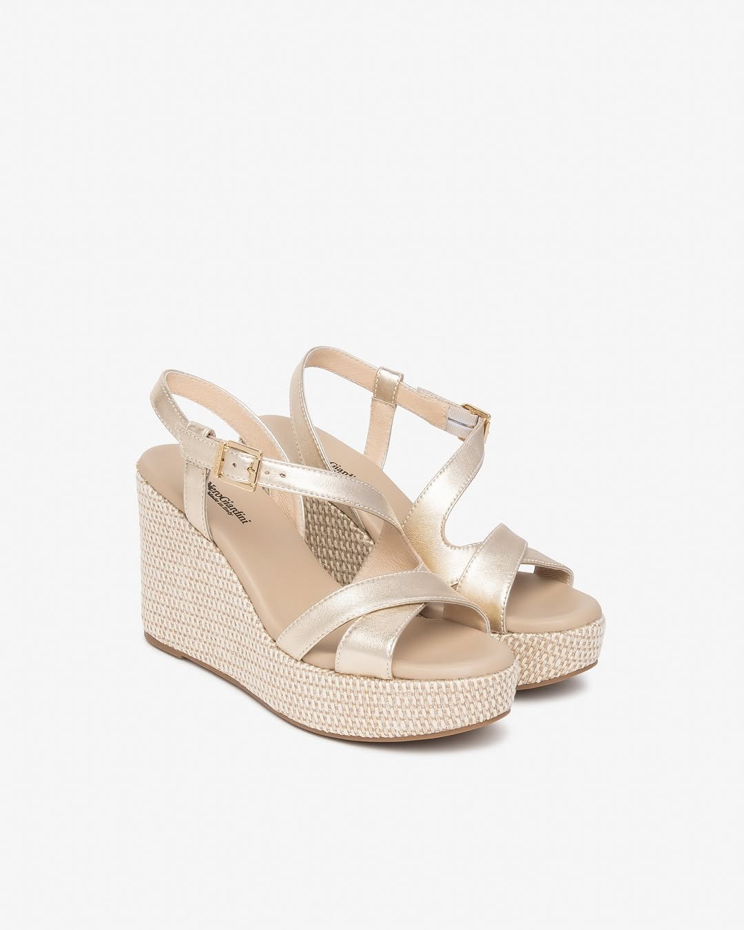 Paire de sandales compensées dorées sur fond blanc