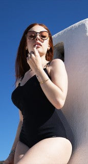 Maillot une-pièce Fairy noir, lunettes de soleil, mur blanc